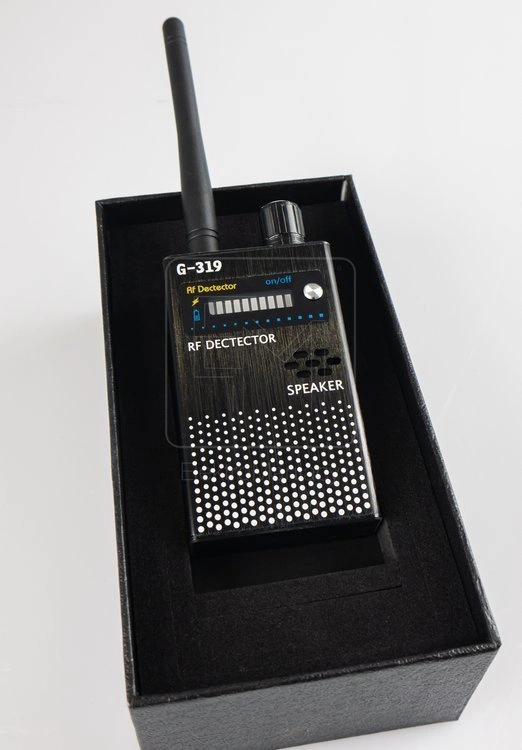 Użytkownik skanuje pokój biurowy wykrywaczem WYK-302 – panel diod LED wskazuje wykrycie sygnału RF, pokrętło regulacji czułości na pierwszym planie